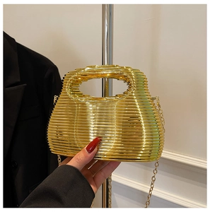 Close-up of golden structured handbag featuring industrial wave texture and chain strap