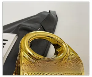 Detail of gold pleated texture handbag with round cutout handle and metallic finish