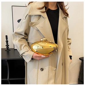 Close-up of polished gold bean-shaped clutch with detachable metal chain strap