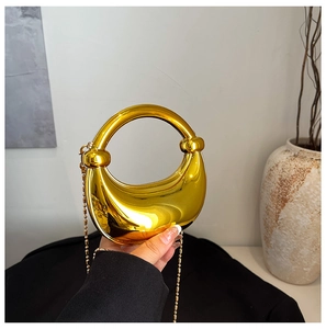 Detail einer glänzenden goldfarbenen Sichelhandtasche mit Kugelkette und integriertem Griff