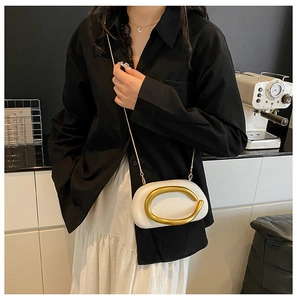 Detail der weißen Abendtasche mit großem goldenem Ringgriff und feiner Kette