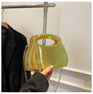 Detail of gold metal evening bag with horizontal stripe hollow design and chain strap