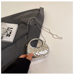 Detail der silbernen Metallic-Muscheltasche mit Rautensteppung und rundem Griff