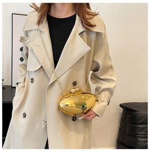 Close-up of golden pebble-shaped clutch bag with polished finish and metal chain strap