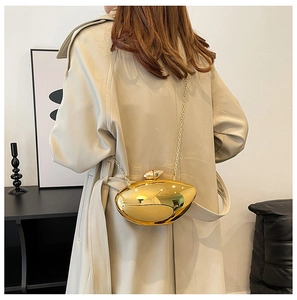 Polished gold pebble-shaped clutch bag with delicate metal chain shown on model