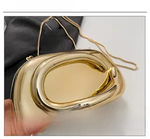 Detail of glossy gold metallic handbag with sleek curves and delicate snake chain strap