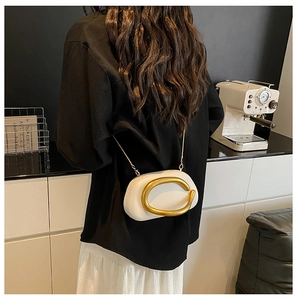 Detail der weißen halbmondförmigen Tasche mit goldener C-Griff und Metallkette
