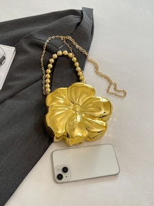 Detailed top view of a gold flower-shaped clutch bag with bead handle and chain strap