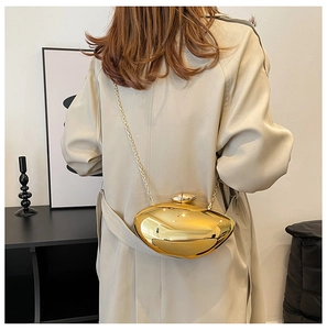 Detail view of a metallic gold pebble shaped crossbody clutch with a fine chain strap