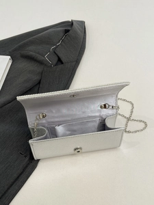 Detail of silver evening clutch interior with pearl trim and magnetic snap closure