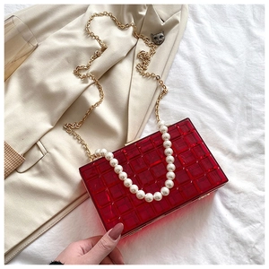 Détail du sac bandoulière rouge en acrylique avec texture matelassée et perles
