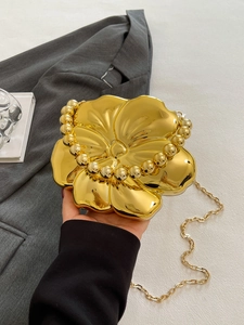 Detail of a gold flower-shaped PVC evening bag with a bead handle and metal chain