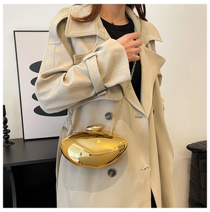 Detail view of a sculptural gold metallic crossbody bag with mirror finish and chain