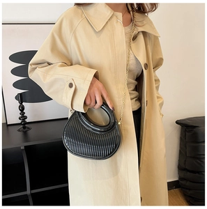Close-up of black pleated half-moon handbag with gold chain strap and textured surface