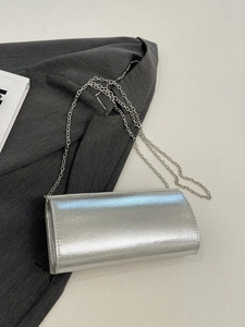 Silver glossy rectangle clutch bag with pearl trim on a grey suit jacket background