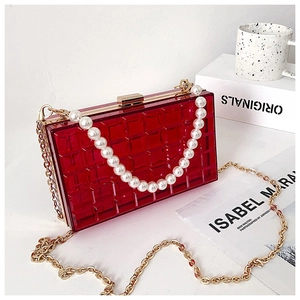 Détail du sac boîte rouge en acrylique avec texture matelassée, perle et chaîne dorée