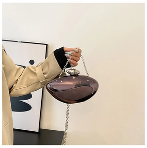 Detail of burgundy pebble-shaped evening clutch with silver chain and metallic finish