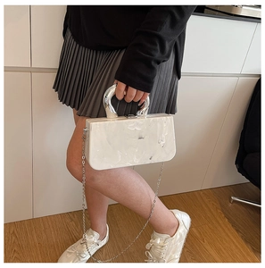 Détail d'un sac à main en acrylique marbré blanc avec poignée en argent et chaîne