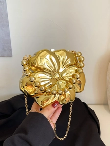 Detailed close-up of a high-shine golden flower evening bag with elegant dual chain straps