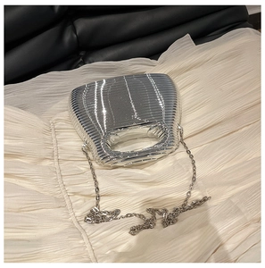 Close-up of silver wavy texture evening bag with metallic finish and chain strap detail