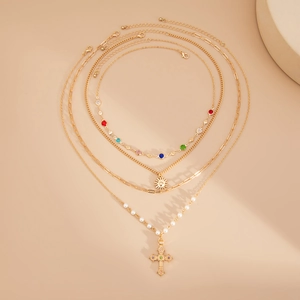 Détail de l'ensemble de colliers superposés avec pendentif croix, perles et gemmes colorées