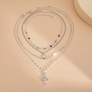 Détail d'un ensemble de 4 colliers superposés avec cristaux colorés, pendentifs soleil et croix