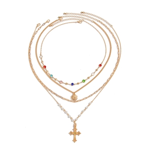 Four-layer gold necklace set featuring cross pendant, pearl chain, and sun charm detail