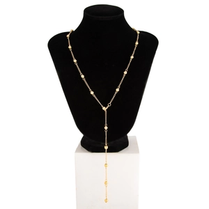 Detail view of the long golden Y-shaped necklace with polished beads on a black bust