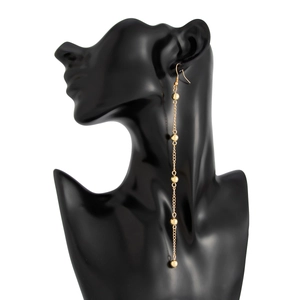 Close-up of minimalist long gold bead tassel earrings with five beads on a model head