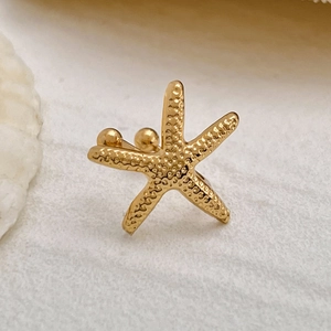 Makro-Detail des goldenen Seestern-Ohrclips mit lebensechter Textur und Metall-Finish
