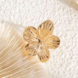 Macro shot of a golden flower earring with radiant texture on a white seashell