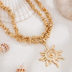 Détail du collier pendentif soleil doré avec texture spirale et perles dorées