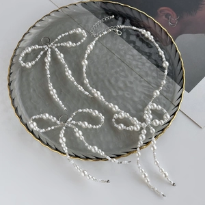 Detailed view of pearl bow necklace and earrings on a luxury gray glass tray