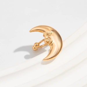 Detailaufnahme von goldenem Mondsichel-Piercing mit Gesicht und polierter Oberfläche