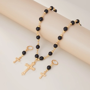 Vue détaillée d'une parure de bijoux religieux perlée avec pendentifs croix dorés sur socle