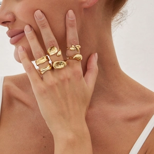 Close-up of golden irregular geometric rings with hammered texture on model hands