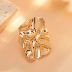 Macro view of wide irregular wrinkled golden ring with liquid metal texture on warm background