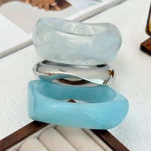 Détail de joncs empilés en résine irrégulière et métal argenté avec texture ondulée