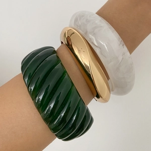 Close-up of three-piece chunky resin and gold metal bangle set for women in high-fashion style
