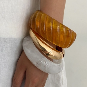 Detailed shot of resin bangles with marble texture, amber ribs and gold metal finish