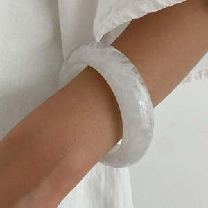 Detail of white translucent resin bangle with ice-cracked texture worn on wrist