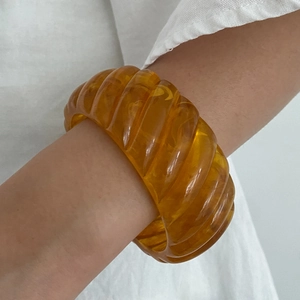 Detailed view of amber resin chunky bangle featuring a unique spiral texture design