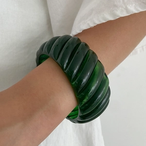 Close-up of a dark green translucent resin bangle with unique vertical stripe texture