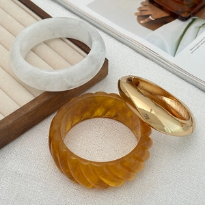 Detailed view of resin marble, amber texture and gold metal chunky bangles set