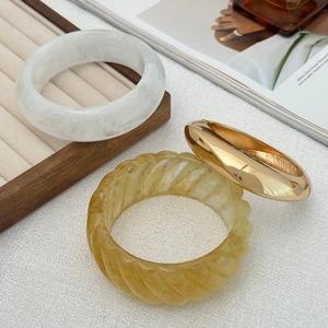 Detail of resin marble, gold metal and amber twisted bangles on a jewelry tray
