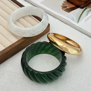 Three-piece bangle set featuring marble resin, gold-tone metal, and green swirl texture