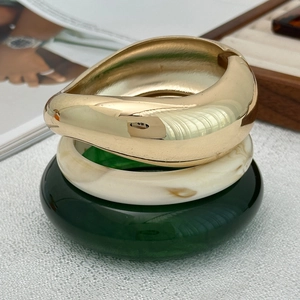 Close-up of three stacked bangles featuring gold metal and marbled resin textures