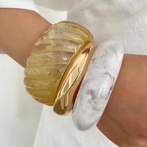 Three-piece stackable bracelet set featuring amber resin and polished gold metal bangles
