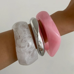 Close-up of minimalist resin and silver metal bangles set on woman's wrist