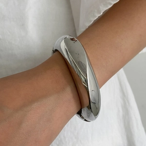 Minimalist irregular twisted silver metal bangle with polished liquid metal finish